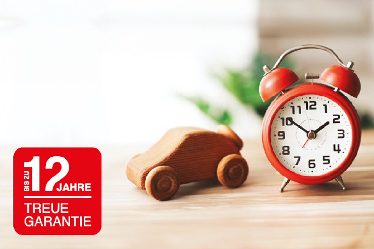 Bild zeigt ein Holzauto neben einer Uhr