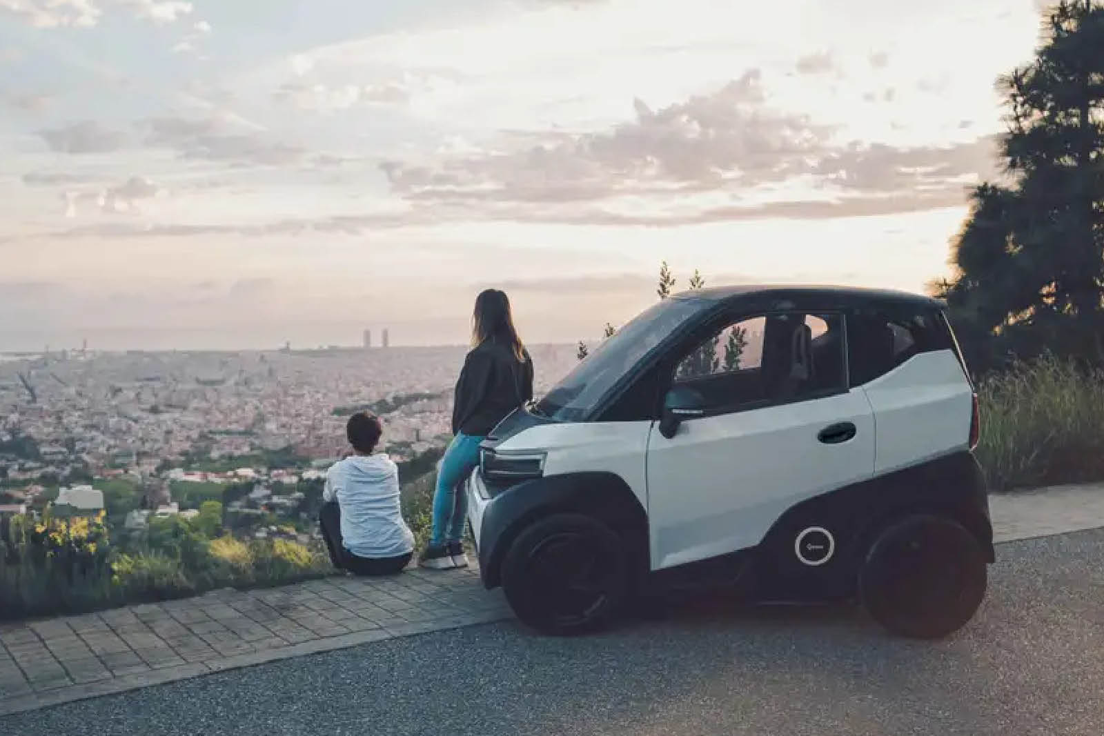 Junge und Mädchen schauen auf die Stadt von Aussichtspunkt, sie lehnt am Auto.
